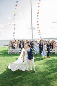 A bride and groom exit their nautical wedding ceremony at American Yacht Club. Photo by Kelly Kollar Photography.