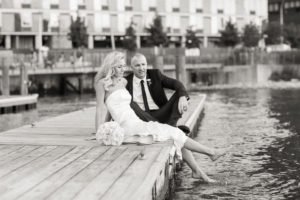 A bride and groom sit on the dock in New York City at their wedding. Photo by Kelly Kollar Photography.