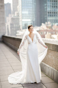 A bride poses on the balcony at New York Athletic Club in Manhattan on her wedding day. Photo by Kelly Kollar Photography.