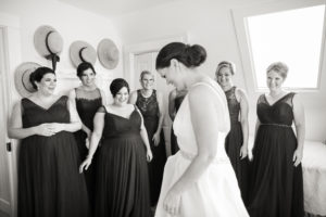 A group of bridesmaids react to the bride in her wedding dress. Photo by Kelly Kollar Photography.