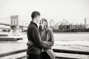 An engaged couple in the South Street Seaport in Manhattan, with views of The Brooklyn Bridge. Photo by Kelly Kollar Photography.