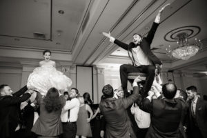 A candid of a bride and groom doing the hora at their Jewish wedding at The Hilton Pearl River in New York. Photo by Kelly Kollar Photography.