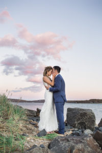 A bride and groom watch the sunset on their wedding day at Peconic Bay Yacht Club on the North Fork of Long Island. Photo by Kelly Kollar Photography.
