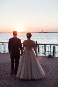 A bride and groom watch the sunset from Liberty Warehouse in Brooklyn. Photo by Kelly Kollar Photography.