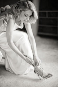 A bride puts on her shoe before her wedding in Manhattan. Photo by Kelly Kollar Photography.