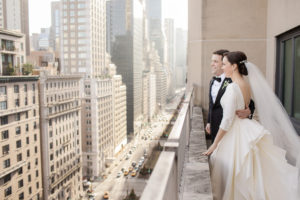 A bride and groom on their wedding day on a balcony the The Lowes Regency in Manhattan. Photo by Kelly Kollar Photography.