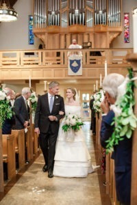 A bride walks down the aisle with her father at her wedding ceremony in Connecticut. Photo by Kelly Kollar Photography.