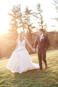 A bride and groom on their wedding day walking in the sunset at Natirar Mansion in New Jersey. Photo by Kelly Kollar Photography.