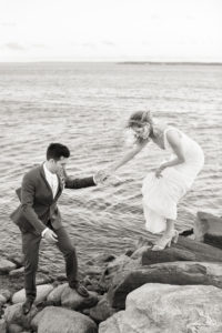 A bride and groom on the rock by the ocean at Peconic Bay Yacht Club in The North Fork on Long Island. Photo by Kelly Kollar Photography.