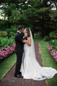 A bride and groom on their wedding day in the garden at Pleasantdale Chateau in New Jersey. Photo by Kelly Kollar Photography.