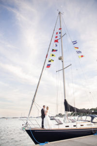 A bride and groom on a sailboat on their wedding day at Riverside Yacht Club in Connecticut. Photo by Kelly Kollar Photography.