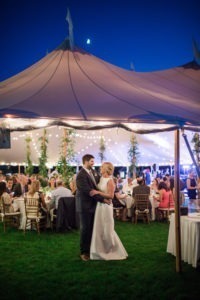 A bride and groom at their tented wedding reception at Shelter Harbor Golf Club in Rhode Island. Photo by Kelly Kollar Photography.