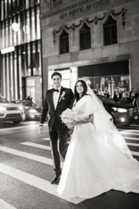 A bride and groom cross the street in Manhattan on their wedding day at The University Club. Photo by Kelly Kollar Photography.
