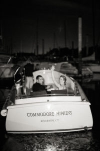 A bride and groom exit their wedding reception by boat at Riverside Yacht Club in Connecticut. Photo by Kelly Kollar Photography.