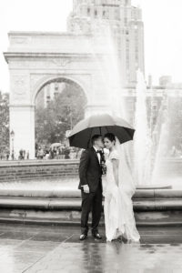 A bride and groom in the rain on their wedding day in Washington Square Park in Manhattan. Photo by Kelly Kollar Photography.